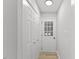 Hallway featuring light wood flooring, white walls, multiple closets, and a door with glass inserts at 1801 Sagamore Ct, Raleigh, NC 27604