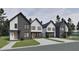 A full street view of townhomes with modern architecture, complemented by lush landscaping and concrete driveways at 1804 Pershing Rd, Raleigh, NC 27608