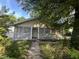 A single-story house with light-yellow siding, overgrown landscaping and a concrete walkway to the front door at 2302 Chautauqua Ave, Durham, NC 27707