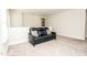 Carpeted loft area featuring a comfortable black leather couch with decorative pillows at 2918 Heirloom Way, Apex, NC 27502