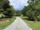 Long gravel driveway leading to a home surrounded by lush greenery and mature trees at 3110 Fieldstone Ln, Mebane, NC 27302