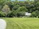 Spacious green lawn with a view of the brick home nestled among mature trees at 3110 Fieldstone Ln, Mebane, NC 27302