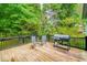 Back deck featuring chairs and a grill, with a wooded view beyond the railing at 318 Fieldstone Dr, Burlington, NC 27215