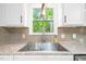 Close-up of the kitchen sink featuring granite countertops and a window view of the greenery outside at 318 Fieldstone Dr, Burlington, NC 27215