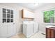 Bright laundry room with white washer and dryer, cabinets, and natural light from the window at 318 Fieldstone Dr, Burlington, NC 27215