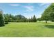 Expansive lawn area showcasing lush green grass and mature trees under a clear blue sky at 4005 Olde Waverly Way, Fuquay Varina, NC 27526