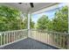 Relaxing covered porch with brick-laid flooring and white railing overlooking lush greenery at 405 Commons Walk Cir, Cary, NC 27519