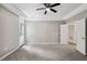 Large bedroom with neutral walls, plush carpet, ceiling fan, and multiple access doors at 6 Danesfield Ct, Durham, NC 27707