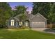 A beautiful one-story house with gray siding, blue shutters, manicured lawn and a two-car garage during sunset at 6 Danesfield Ct, Durham, NC 27707