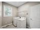 Bright laundry room with modern washer and dryer, tiled flooring, and ample shelf space for storage at 6 Danesfield Ct, Durham, NC 27707
