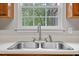 Close-up of a stainless steel kitchen sink with a large window view at 6927 Beaverwood Dr Dr, Raleigh, NC 27616