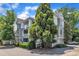 Attractive gray condos with brick driveways are surrounded by mature trees and manicured landscaping at 700 Bishops Park Dr # 302, Raleigh, NC 27605