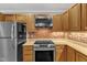 Bright kitchen featuring stainless steel appliances, wood cabinets and exposed brick accents at 700 Bishops Park Dr # 302, Raleigh, NC 27605