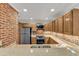 Well-lit kitchen featuring stainless steel appliances, wood cabinetry, granite countertops, and exposed brick at 700 Bishops Park Dr # 302, Raleigh, NC 27605