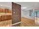 Open-concept living area with hardwood floors, a brick accent wall, and sliding doors to a balcony at 700 Bishops Park Dr # 302, Raleigh, NC 27605