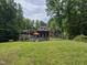 Expansive backyard view featuring a home, pool, deck, trampoline and mature trees at 7483 Danford Rd, Burlington, NC 27215