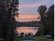 Peaceful sunset view of the lake surrounded by dense trees reflecting off the water at 7483 Danford Rd, Burlington, NC 27215
