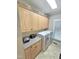 Bright laundry room with tile flooring, light wood cabinets, countertop, and a front-loading washer and dryer at 7483 Danford Rd, Burlington, NC 27215
