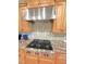 Stainless steel stove top and hood in a spacious kitchen with a beautiful backsplash at 7483 Danford Rd, Burlington, NC 27215