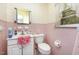 Pink tiled bathroom with floral wallpaper and white fixtures at 9751 N Highway 96, Selma, NC 27576