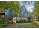 Backyard of blue home with brick foundation, small brick patio, and mature landscaping at 102 W Weatherspoon St, Sanford, NC 27330