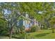 Blue home with a lush front yard, red door, and screened porch, surrounded by green trees at 102 W Weatherspoon St, Sanford, NC 27330