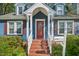 Inviting home entrance featuring a red front door, brick steps, and lush landscaping enhancing curb appeal at 102 W Weatherspoon St, Sanford, NC 27330