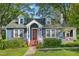 Charming blue home boasts a red front door, dormer windows, and brick steps leading to the entrance at 102 W Weatherspoon St, Sanford, NC 27330