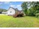 View of the home from the spacious backyard featuring a deck, lawn and mature trees at 110 Oak Park Dr, Benson, NC 27504