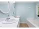 Clean bathroom with dual sinks, white cabinets, white bathtub, and neutral tile flooring at 110 Oak Park Dr, Benson, NC 27504