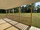 Back porch featuring wood flooring and posts overlooking the grassy backyard and wooded area at 111 Mahogany Way, Four Oaks, NC 27524