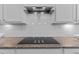 A close up of a cooktop with white cabinets and white subway tile backsplash and granite countertops at 1112 Monterey Bay Dr, Wake Forest, NC 27587