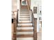 Staircase showcasing hardwood steps, white risers, and dark metal railings, with views to the kitchen and dining room at 1218 Rogers Farm Rd, Wake Forest, NC 27587