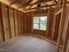 Unfinished bedroom shows a window and exposed framing, ready to be designed into a personalized and cozy space at 136 Tuskeegee Dr, Smithfield, NC 27577