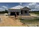 New construction of a single-Gathering home with builder carrying a ladder in the front of the house at 136 Tuskeegee Dr, Smithfield, NC 27577
