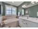 This bathroom boasts a soaking tub under a window with plantation shutters and a white vanity with double sinks at 137 Cofield Cir, Durham, NC 27707