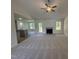 Open-concept living area with a fireplace, ceiling fan, and seamless flow into the kitchen and outdoor deck at 171 Tulipfield Way, Benson, NC 27504