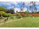 Professionally landscaped backyard with a wooden pergola, lush trees, and manicured grounds at 182 Brendamoore Ct, Fuquay Varina, NC 27526