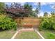 Landscaped backyard with wood privacy fence and brick-lined walkway leading to a decorative red bench at 182 Brendamoore Ct, Fuquay Varina, NC 27526