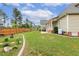 Green home exterior with a well-maintained lawn, wooden privacy fence, and garden area with flower beds at 182 Brendamoore Ct, Fuquay Varina, NC 27526