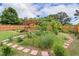 Professionally landscaped backyard with a wooden pergola, walkways, and lush greenery at 182 Brendamoore Ct, Fuquay Varina, NC 27526