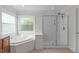 Bright bathroom featuring a soaking tub with a window and a glass enclosed shower with a chrome showerhead at 2003 Red Sage Ct, Apex, NC 27502