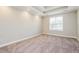 Bright bedroom featuring neutral carpet, tray ceilings, and a sun-filled window at 234 Lars Ln, Garner, NC 27529