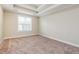 Bright bedroom featuring neutral carpet, tray ceilings, and a sun-filled window at 234 Lars Ln, Garner, NC 27529
