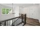Hallway with a black metal railing, wood floors, a chandelier, and a window with outside views at 2617 Packhouse Rd, Zebulon, NC 27597