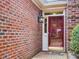 Close-up of the beautiful brickwork and red front door with decorative glass and a welcoming lantern at 3347 Ridgecrest Ct, Raleigh, NC 27607