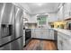 Bright kitchen boasts stainless steel appliances, white cabinetry, and a window over the sink with hardwood floors at 3541 E Jameson Rd, Raleigh, NC 27604