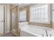 Bright bathroom features a glass enclosed shower, garden tub, and a privacy window at 4001 Bostwyck Dr, Fuquay Varina, NC 27526