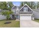 Charming two-story home with stone accents, a two-car garage, a blue front door, and mature landscaping at 4001 Bostwyck Dr, Fuquay Varina, NC 27526
