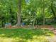Backyard swing set with a playhouse next to trees with grass yard at 4112 Rowan St, Raleigh, NC 27609